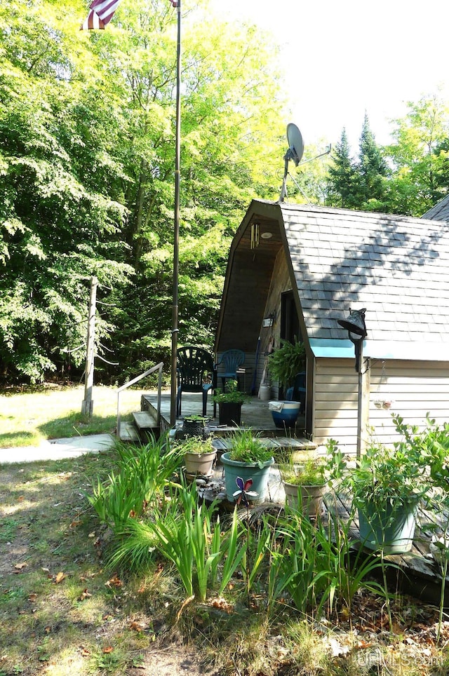 view of side of property with a shingled roof and a deck