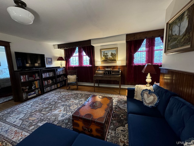 living room featuring hardwood / wood-style flooring, a baseboard heating unit, and wood walls