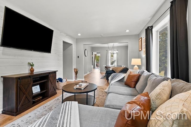 living room featuring a chandelier, wooden walls, and light hardwood / wood-style floors