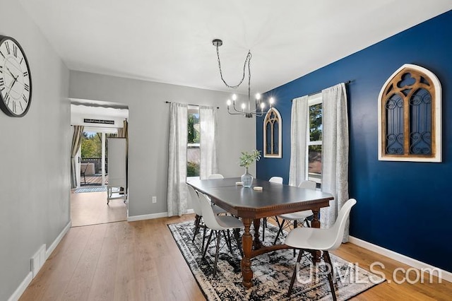 dining area with light wood-type flooring and a chandelier