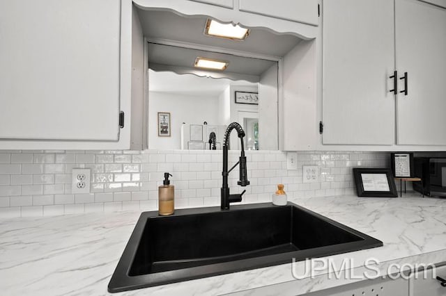 kitchen with sink, light stone countertops, decorative backsplash, and white cabinets