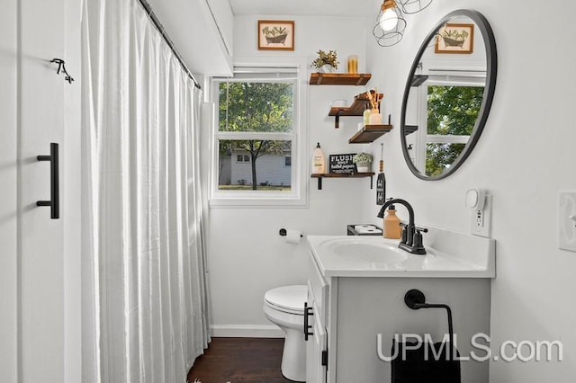 bathroom featuring wood-type flooring, toilet, plenty of natural light, and vanity