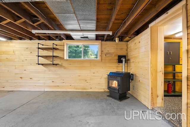 basement featuring wood walls and a wood stove