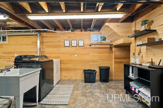 basement with sink, washer and clothes dryer, and wooden walls