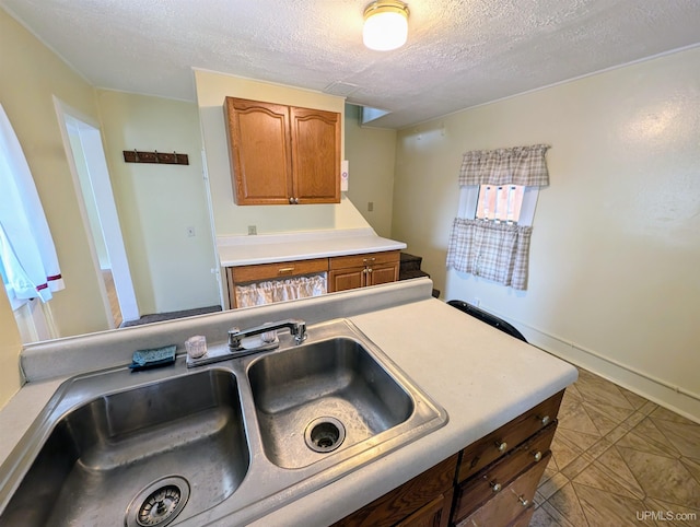 kitchen featuring a textured ceiling, sink, and tile patterned flooring