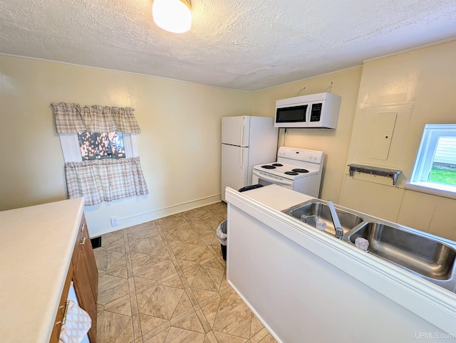 kitchen with white appliances, sink, and a textured ceiling