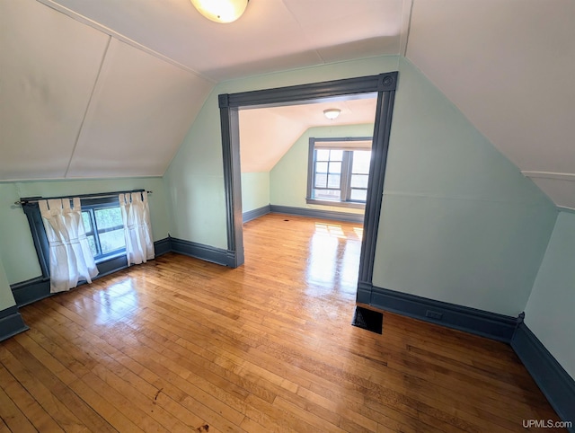 bonus room featuring light wood-type flooring, lofted ceiling, and plenty of natural light