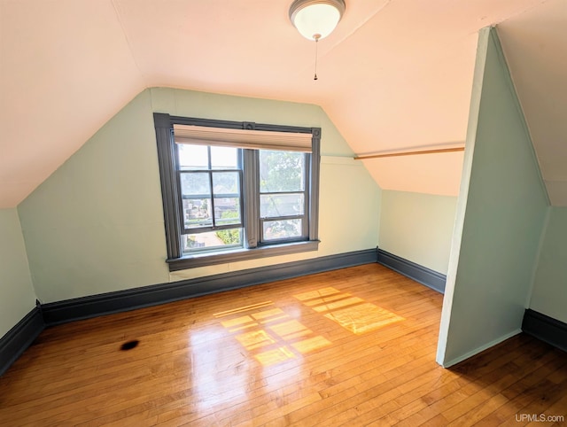 additional living space with lofted ceiling and light hardwood / wood-style flooring