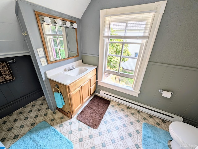 bathroom featuring a wealth of natural light, vanity, toilet, and a baseboard heating unit