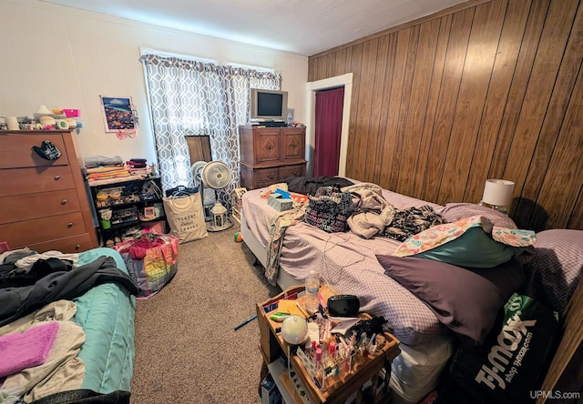 carpeted bedroom featuring wood walls