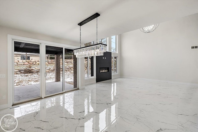 unfurnished dining area featuring a glass covered fireplace, visible vents, baseboards, and marble finish floor