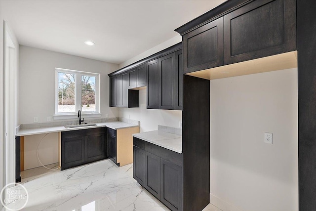 kitchen with light countertops, recessed lighting, marble finish floor, and a sink