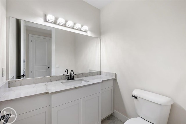 bathroom featuring baseboards, toilet, marble finish floor, and vanity