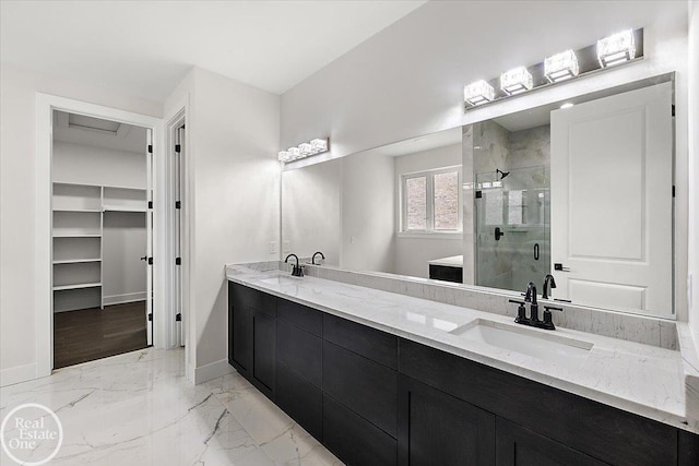 bathroom featuring marble finish floor, a sink, a shower stall, double vanity, and baseboards