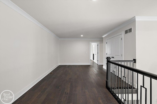 hallway with visible vents, baseboards, dark wood finished floors, crown molding, and an upstairs landing