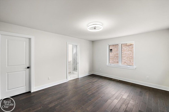 unfurnished room with baseboards and dark wood finished floors