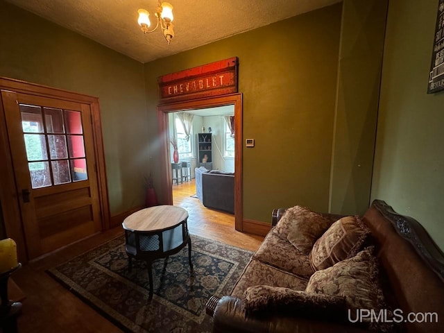 living room with wood-type flooring, a notable chandelier, and a textured ceiling