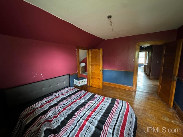 unfurnished bedroom featuring lofted ceiling and hardwood / wood-style flooring