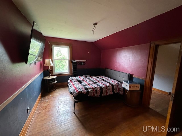 bedroom with lofted ceiling and wood-type flooring