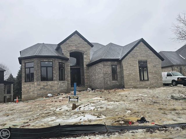 french provincial home with stone siding and roof with shingles