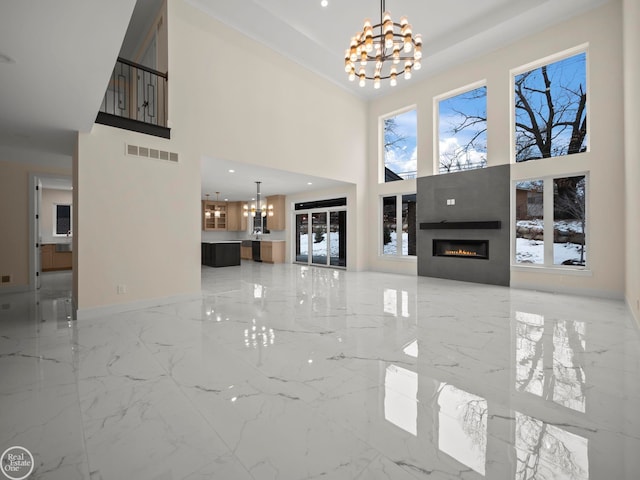 unfurnished living room featuring a towering ceiling and a notable chandelier