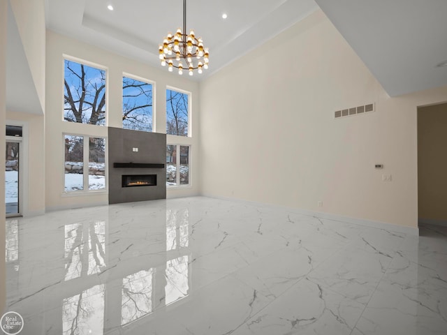 living room featuring a raised ceiling, a high ceiling, and a notable chandelier