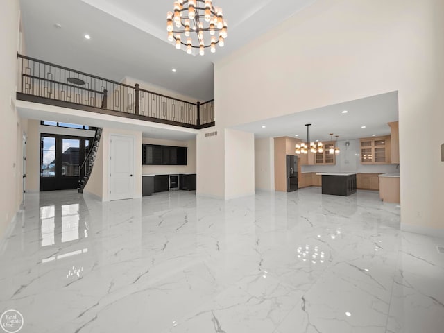 unfurnished living room with french doors, a towering ceiling, and a notable chandelier