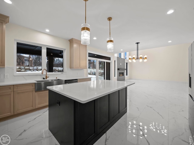 kitchen with sink, an inviting chandelier, decorative light fixtures, light brown cabinetry, and a kitchen island