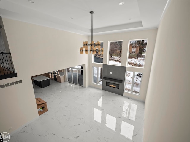 living room with an inviting chandelier and a raised ceiling