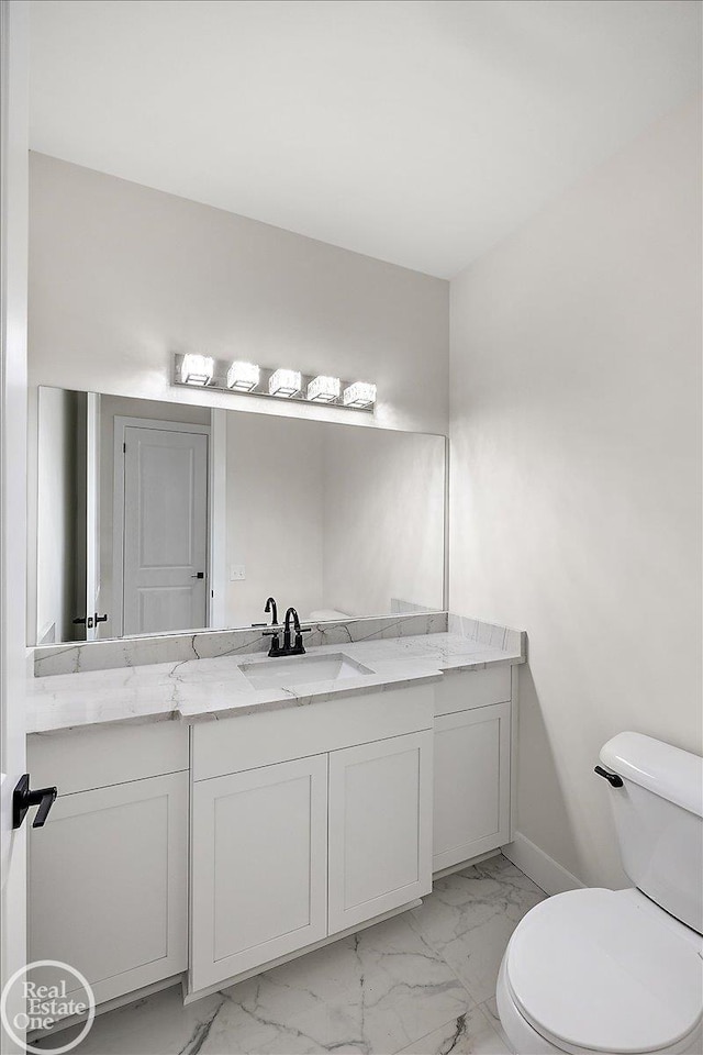 bathroom featuring marble finish floor, baseboards, vanity, and toilet