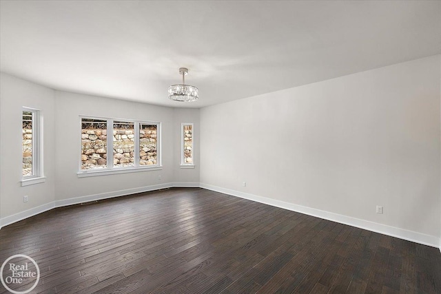 empty room featuring baseboards, visible vents, a chandelier, and dark wood finished floors