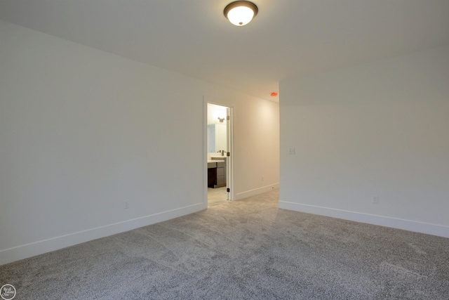 spare room featuring light carpet and baseboards