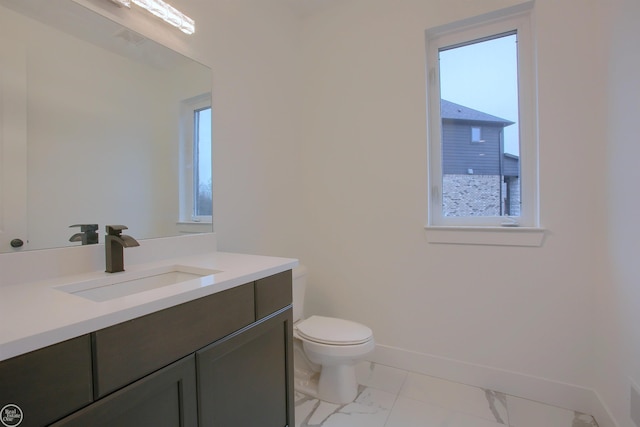 bathroom featuring vanity, toilet, baseboards, and marble finish floor