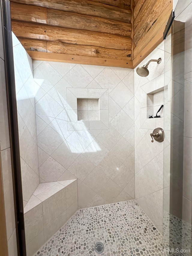 bathroom featuring rustic walls and a tile shower