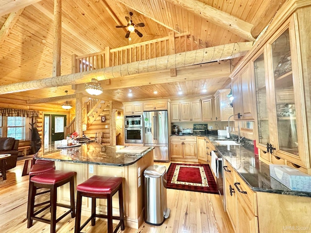 kitchen featuring wood ceiling, stainless steel appliances, dark stone counters, ceiling fan, and a kitchen island