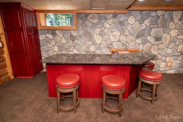 bar featuring carpet, dark stone countertops, and wooden ceiling