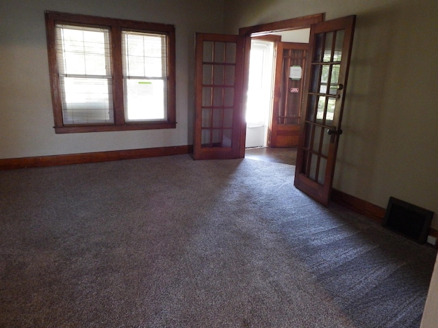 empty room featuring french doors and dark colored carpet