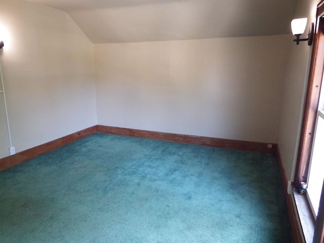 spare room featuring dark carpet and lofted ceiling