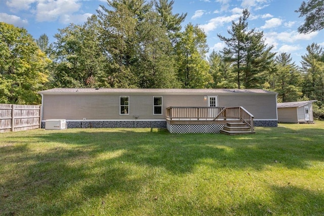 back of property featuring a yard, a deck, and a storage unit