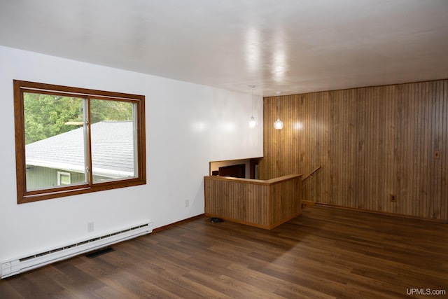 spare room featuring dark hardwood / wood-style flooring, wood walls, and a baseboard radiator