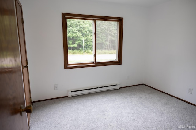 spare room featuring a baseboard heating unit and light colored carpet