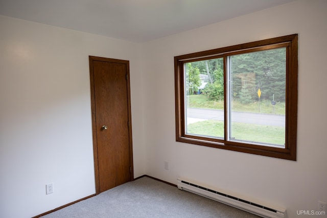 carpeted spare room with plenty of natural light and a baseboard radiator