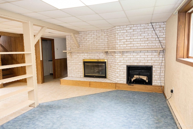 unfurnished living room featuring a paneled ceiling, carpet flooring, and a brick fireplace