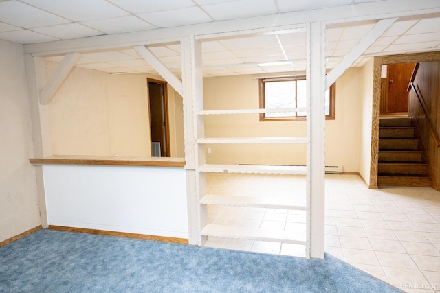 basement with a paneled ceiling, a baseboard radiator, and carpet floors