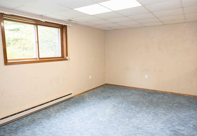 spare room with a baseboard heating unit, a drop ceiling, and carpet floors