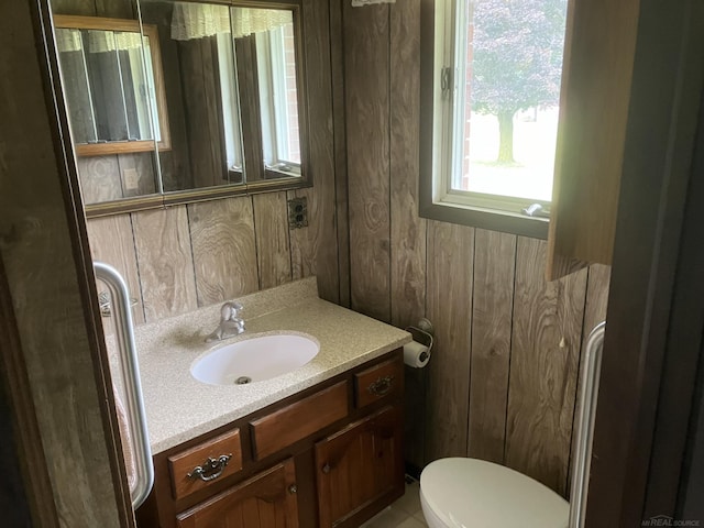 bathroom featuring vanity, toilet, and wooden walls