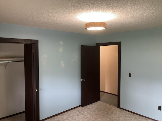 unfurnished bedroom featuring a closet, a textured ceiling, and light colored carpet