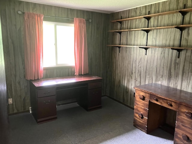 home office with a textured ceiling, wooden walls, and built in desk