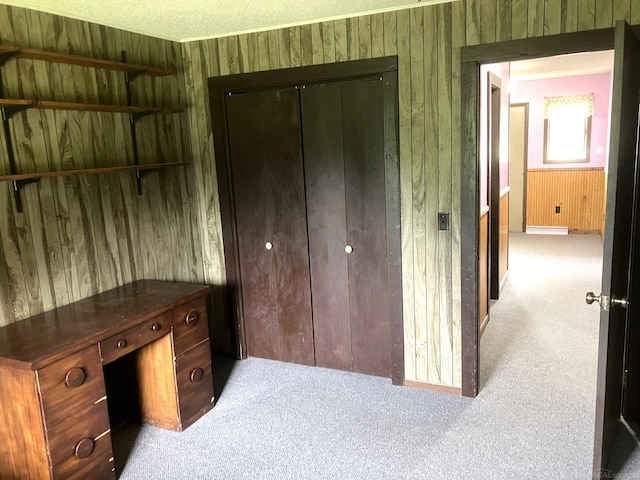 carpeted bedroom with a textured ceiling, a closet, and wood walls