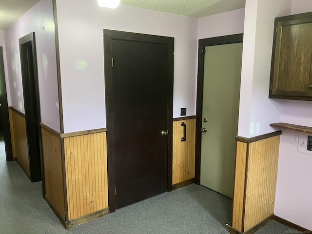 corridor with dark carpet and a textured ceiling